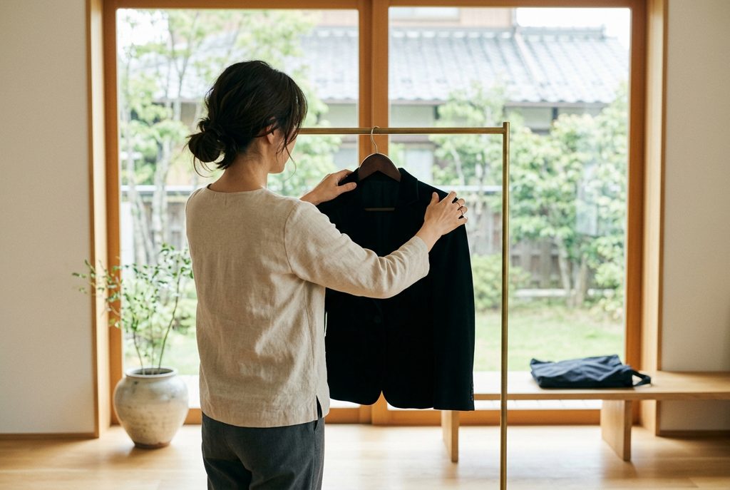 フォーマルドレスをハンガーにかける女性の後ろ姿
