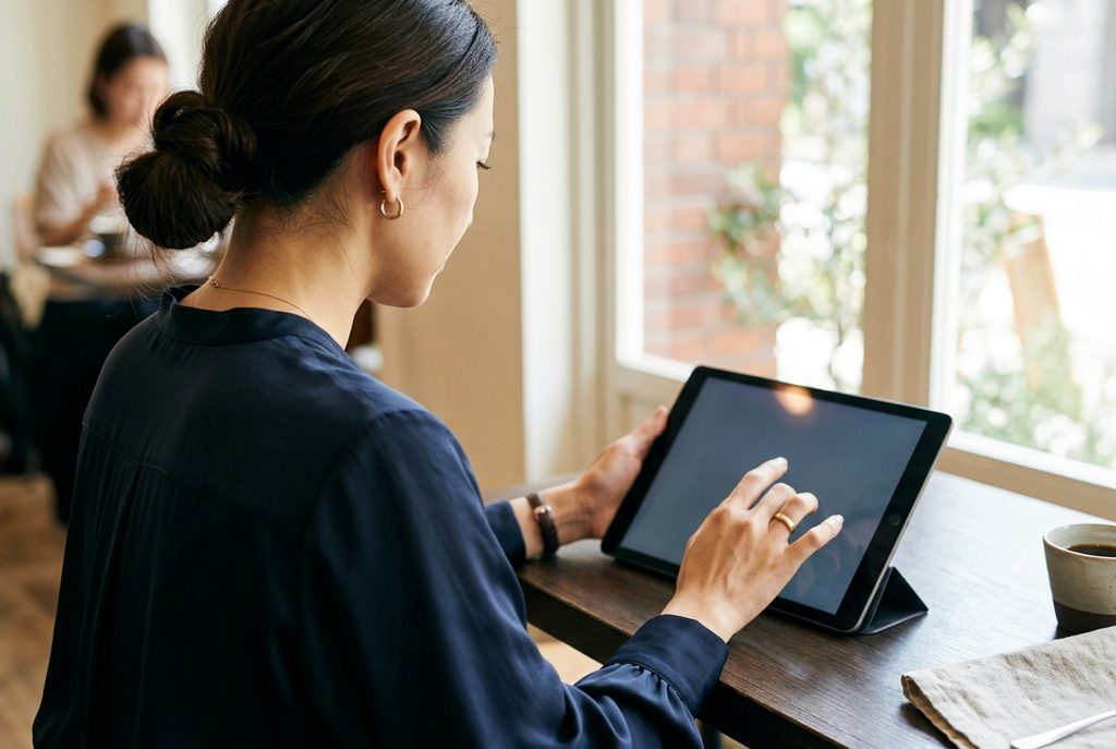 タブレットで情報を確認する女性の後ろ姿